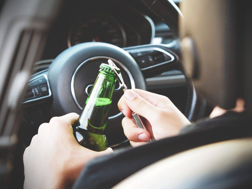 open container laws and penalties in texas - driver opening a bottle while behind the wheel of a car