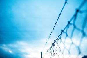 felony or misdemeanor - prison fence with razor wire against sky