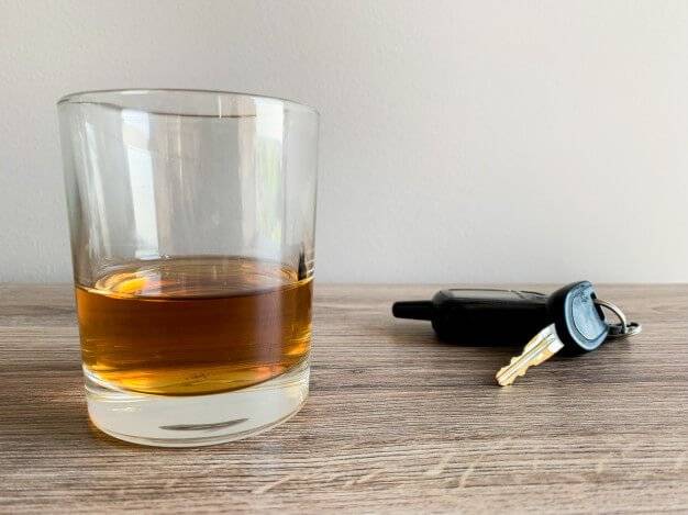 drunk driving concept image - tumbler of alcohol with car keys