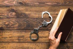the importance of hiring a fort bend assault attorney - handcuffs and book on wooden table