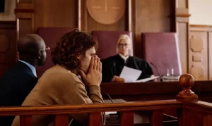 Criminal Defense Blog 15 a man stands in a courtroom, facing trial, representing the choice between a plea bargain and a not guilty plea
