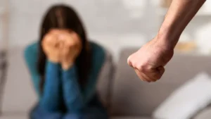 Criminal Defense Blog 26 crying woman with one hand raised, sitting indoors, showing visible distress and emotion.